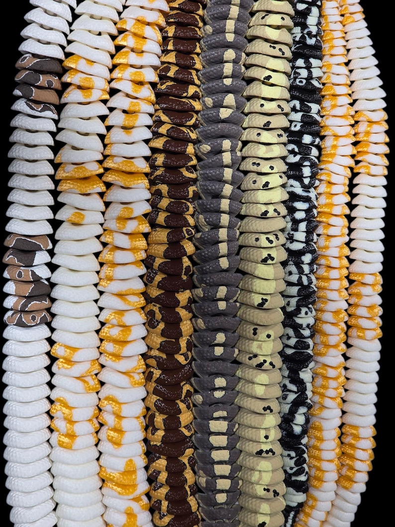 May include: A vertical arrangement of several decorative snake-like items. The items are in various colors and patterns, including white, yellow, brown, gray, and black. The items have a segmented design, resembling a snake's body.