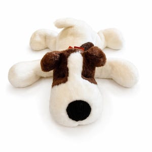 May include: A plush dog toy in white, brown, and black. The dog has floppy ears, a black nose, and a red bow. The toy is lying on its back with its arms and legs outstretched.