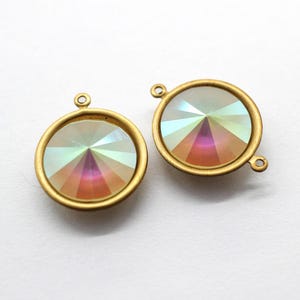 Könnte beinhalten: Zwei runde, irisierende Kristallanhänger mit goldfarbenen Metallrahmen. Jeder Anhänger hat oben eine Schlaufe und an der Seite eine kleine Schlaufe zum Befestigen an Schmuck. Die Kristalle reflektieren einen Regenbogen an Farben.