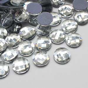 May include: A pile of clear, faceted, round rhinestones with a reflective surface.