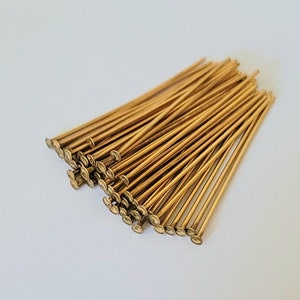 May include: A pile of gold-colored head pins, also known as T-pins, used for crafts and jewelry making.