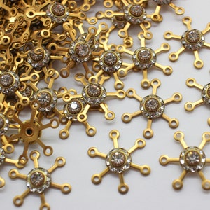 May include: A pile of gold-toned metal snowflake charms with clear rhinestone accents.
