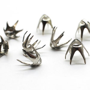 May include: Silver metal cone-shaped embellishments with a starburst design. The embellishments have a hole in the center and are designed for use in crafts and jewelry making.