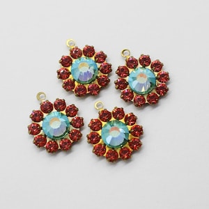 May include: Four gold-tone metal charms with red and blue rhinestones. Each charm features a round, iridescent blue rhinestone surrounded by smaller red rhinestones.