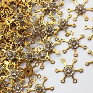 May include: A pile of gold-toned metal snowflake charms with clear rhinestone accents.