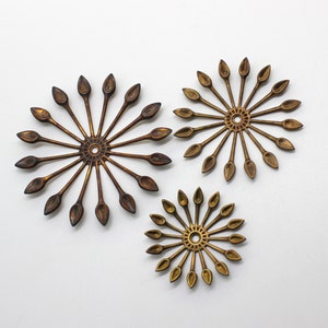 May include: Three gold-toned metal wall decor pieces in the shape of a sunburst with pointed rays.