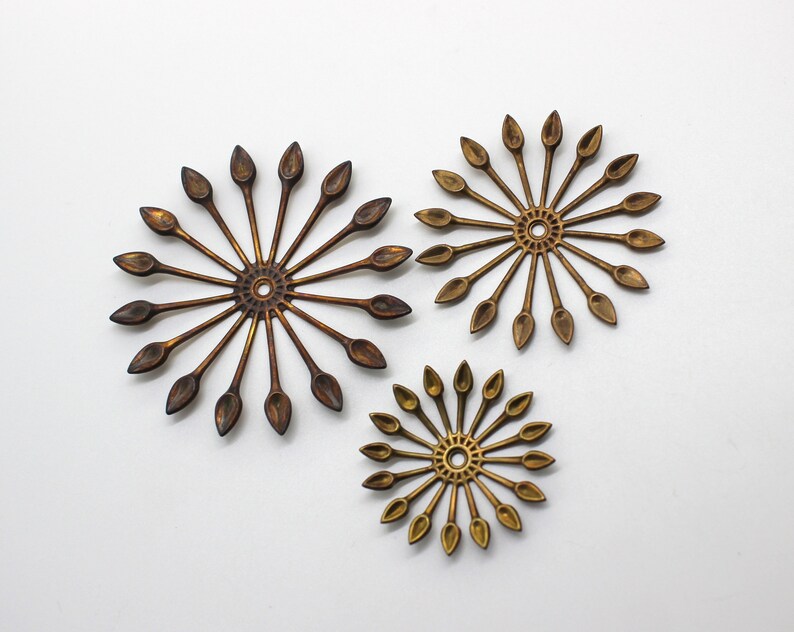May include: Three gold-toned metal wall decor pieces in the shape of a sunburst with pointed rays.