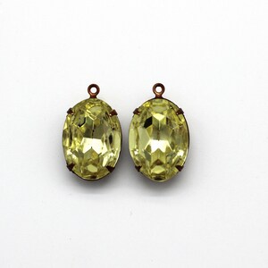 May include: Two oval-shaped, yellow glass pendants with copper-colored metal loops. The pendants have a faceted design.