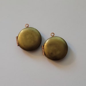 Puede incluir: Dos colgantes de medall&oacute;n redondos de color dorado con una abertura con bisagra. Los medallones tienen un acabado liso y brillante.