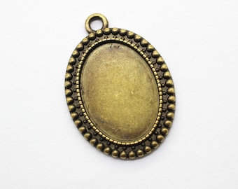 May include: An antique brass-toned oval pendant with a beaded border and a small loop at the top. The pendant has a recessed center, perfect for setting a cabochon or other embellishment. Ideal for jewelry making.
