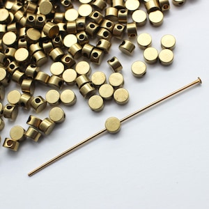 May include: A pile of gold-colored metal beads with a single bead on a thin gold-colored wire.