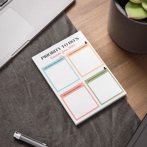 以下が含まれることがあります： 上部に「PRIORITY TO DO'S」というテキストが書かれた、カラフルなグリッドが付いた白いメモ帳。メモ帳には「Samantha Jones, BCBA」というテキストがラベル付けされています。グリッドの各セクションには、「LOW EFFORT/HIGH PRIORITY」、「HIGH EFFORT/HIGH PRIORITY」、「LOW EFFORT/LOW PRIORITY」、「HIGH EFFORT/LOW PRIORITY」というラベルが付けられています。