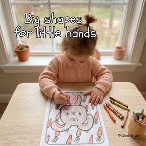 May include: A child coloring a bunny and carrot drawing with crayons. The image includes the text "Big shapes for little hands". A wooden cup holds several crayons. The child is wearing a peach-colored sweater.