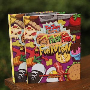 May include: Two cookbooks titled "Toe Jam & Earl's Funky Fresh Foods of Funkotron" are shown. The covers display vibrant illustrations of pizza, hot dogs, and other food items against a purple backdrop. The book's title is in a playful font.
