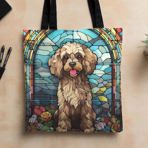 May include: A brown and white poodle dog with a stained glass background. The dog is sitting in front of a stained glass window with a blue, green, and yellow design. The dog has a pink tongue sticking out and is looking at the camera.