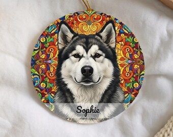 May include: A round ceramic ornament featuring a detailed portrait of a black and white Alaskan Malamute dog. The background displays a vibrant, multi-coloured stained glass pattern. The name Sophie is printed in black script at the bottom centre.
