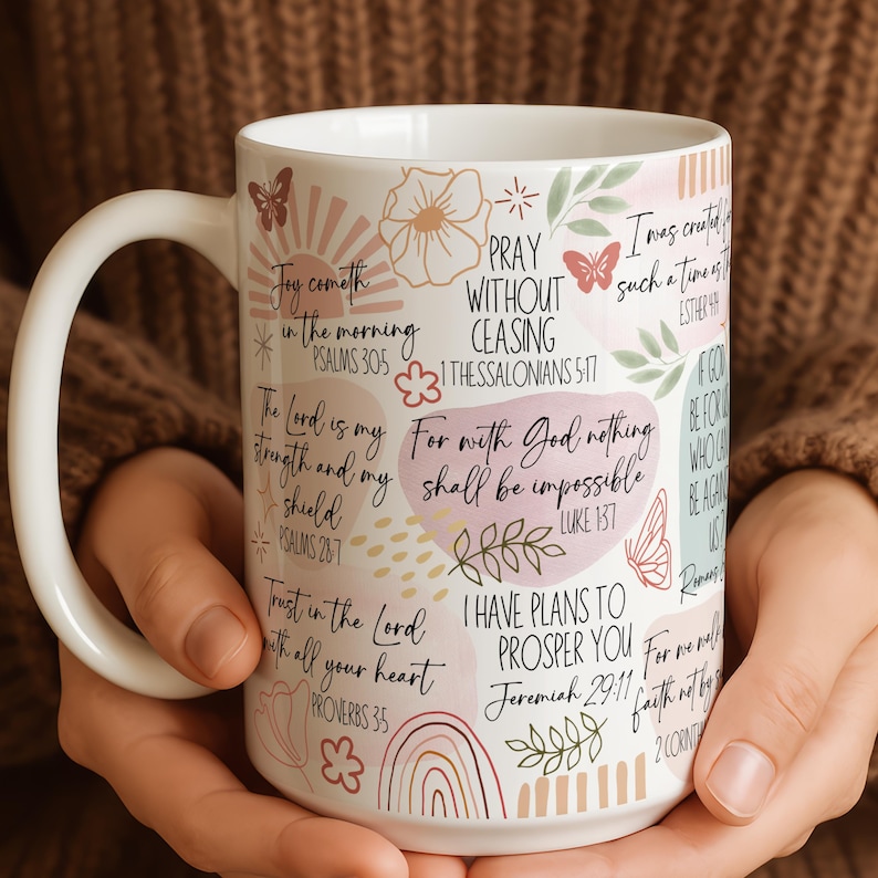 May include: A white ceramic mug with a black handle and the text "But First, Coffee" in a bold, black font. The mug is set against a blurred background, suggesting a cosy setting.
