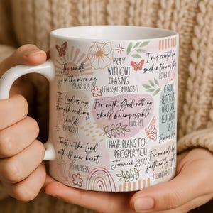 May include: A white ceramic mug with a black handle and the text "But First, Coffee" in a bold, black font. The mug is filled with a dark liquid, likely coffee, and rests on a light-coloured surface.