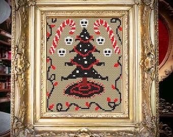 May include: Cross-stitch art in a gold ornate frame. The artwork features a black Christmas tree with skull ornaments, red string lights, and candy canes. The background is a neutral tan color.