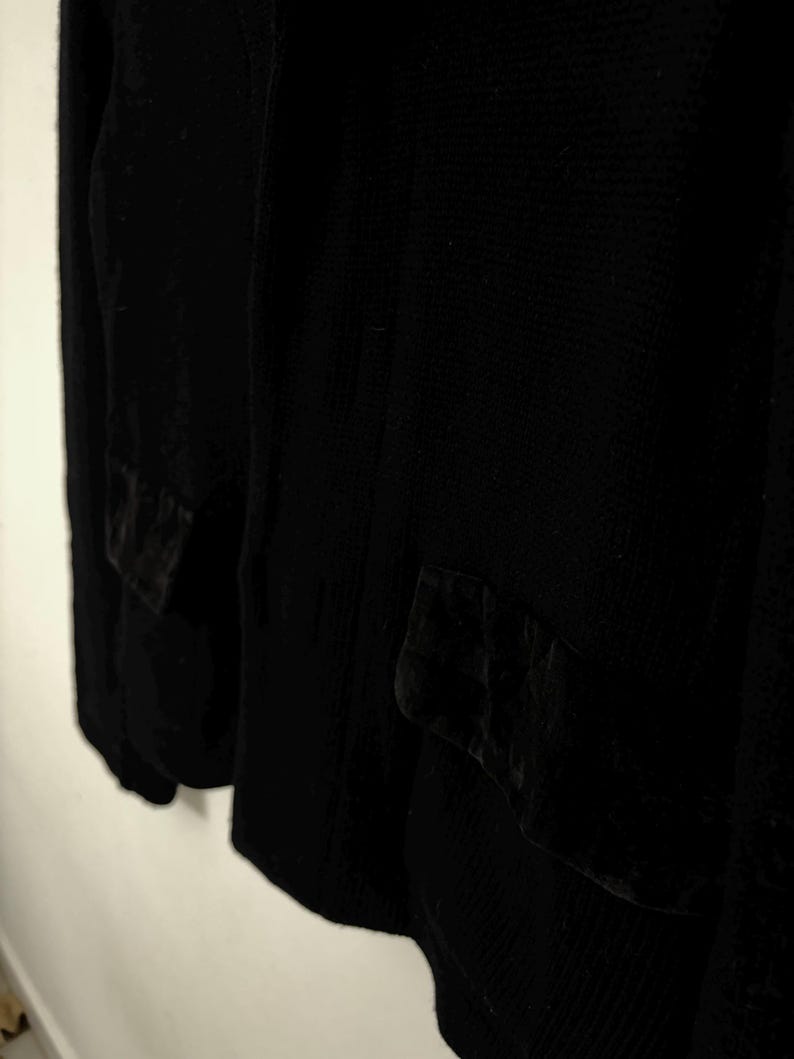 May include: A black blazer with two front pockets. The blazer is made of a textured fabric and has a classic design. The pockets have a velvet-like texture. The blazer is a versatile piece of clothing.