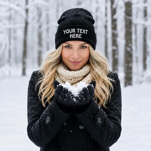 May include: A black knit beanie featuring the white embroidered text YOUR TEXT HERE on the front cuff. The hat is made of a ribbed fabric and is designed to be worn as a winter accessory to provide warmth and coverage for the head during cold weather.