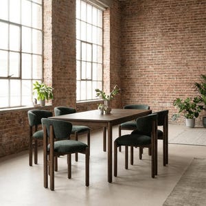 May include: A dark wood dining table with six chairs. The chairs have dark wood frames and dark green upholstered seats and backs. The room has exposed brick walls and large windows.