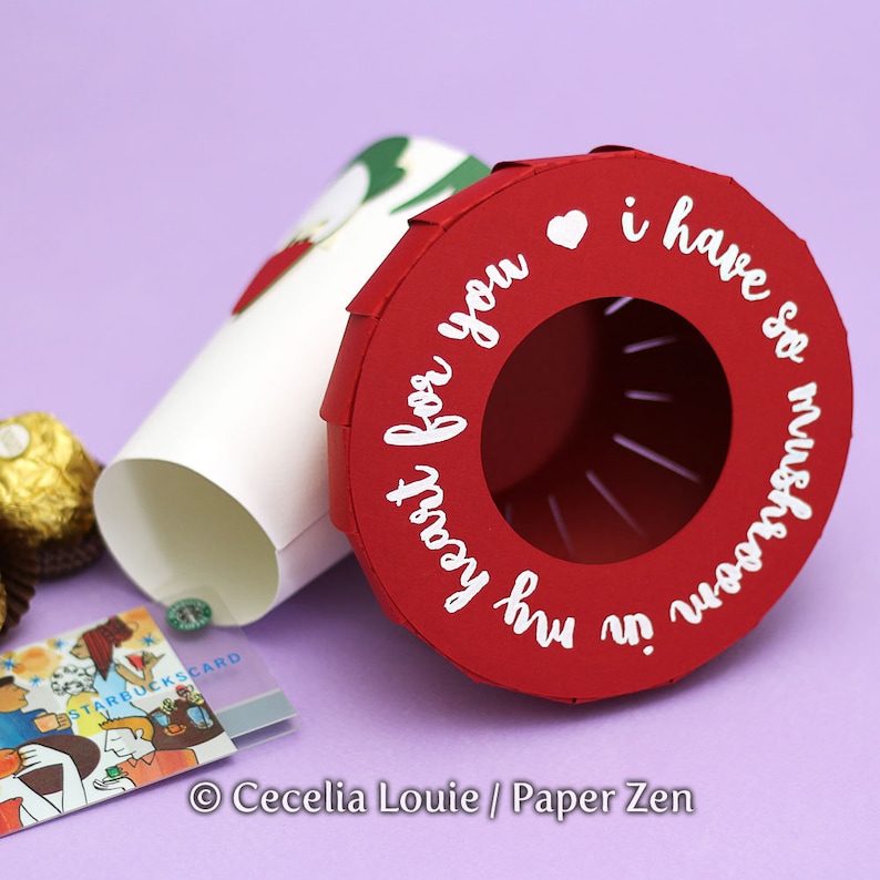 May include: Red paper cup with a white heart and the text "my heart for you" and "i have so much for you" on the side. The cup is open and there is a white paper cup inside.