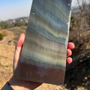 May include: A large, rectangular piece of iridescent, multi-colored glass with a dark gray background. The glass has a wavy pattern and is marked with the number "24".