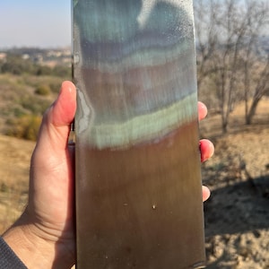 May include: A rectangular piece of metal with a brushed finish. The metal has a rainbow of colors, including blue, green, brown, and purple.