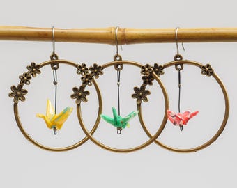 Miniature hand folded Japanese origami paper cranes encased in an ecofriendly varnish seal and dangling within bronze floral hoop earrings