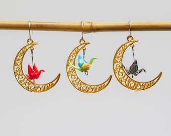Miniature hand folded Japanese origami paper cranes encased in an ecofriendly varnish seal and dangling within gold crescent moon earrings