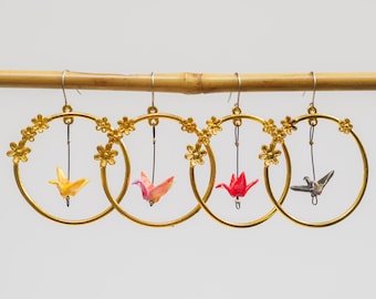 Miniature hand folded Japanese origami paper cranes encased in an ecofriendly varnish seal and dangling within gold floral hoop earrings