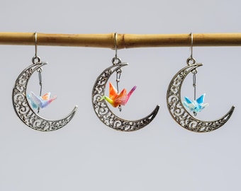 Miniature hand folded Japanese origami paper cranes encased in an ecofriendly varnish seal and dangling within silver crescent moon earrings