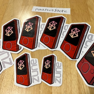 May include: Nine red and white stickers with a stylized image of a Zune MP3 player. The stickers have the word "Zune" printed on them in a gray font.