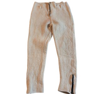 May include: Light beige quilted trousers with a black zip fly and black zips at the ankles. The trousers have a textured surface and a relaxed fit, suitable for casual wear.