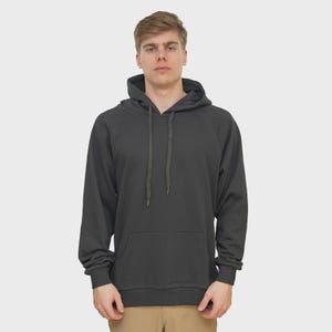May include: A charcoal gray hoodie with a drawstring hood and a kangaroo pocket. The long-sleeved sweatshirt is made of a soft material and is suitable for casual wear. The model is wearing khaki pants.