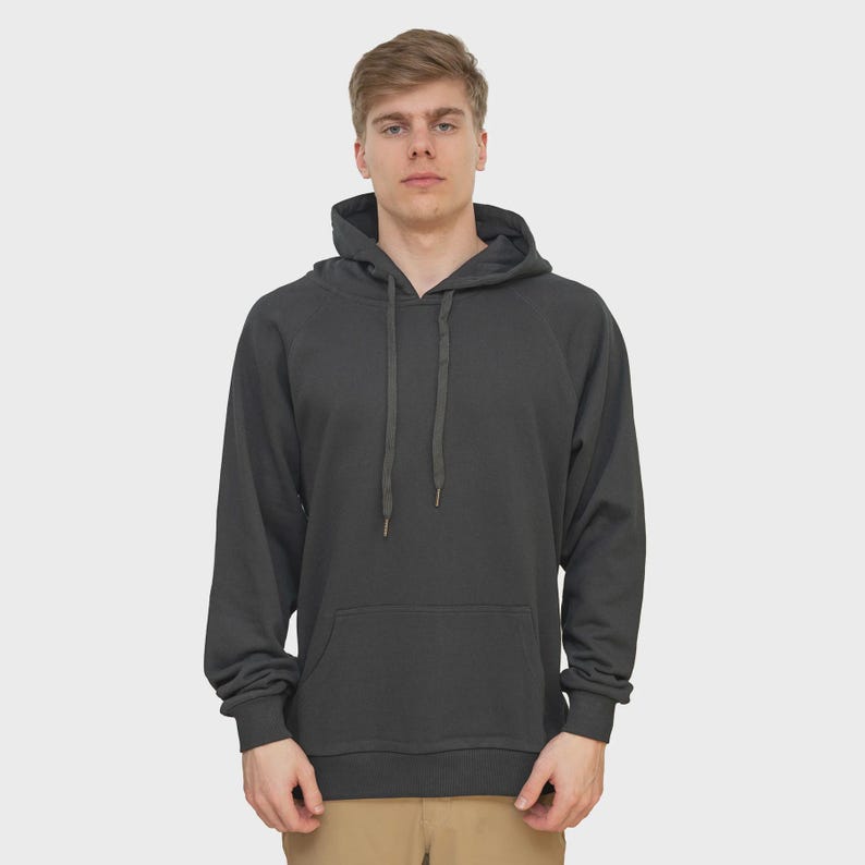 May include: A charcoal gray hoodie with a drawstring hood and a kangaroo pocket. The long-sleeved sweatshirt is made of a soft material and is suitable for casual wear. The model is wearing khaki pants.