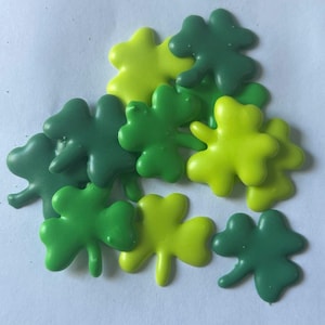 May include: A collection of green and yellow shamrock-shaped sprinkles, perfect for decorating cakes and cupcakes for St. Patrick's Day.