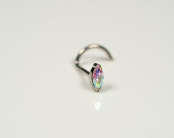 Puede incluir: Un aro de nariz plateado con una piedra preciosa iridiscente en forma de marquesa.