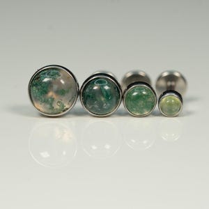 May include: Set of five silver body jewelry pieces with green and white agate stones. The stones are round and have a domed shape. The jewelry is arranged in order of size, with the largest stone on the left and the smallest stone on the right.