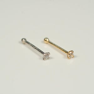 Puede incluir: Dos anillos de nariz con una peque&ntilde;a piedra preciosa transparente en cada uno. Un anillo es de plata y el otro es de oro.