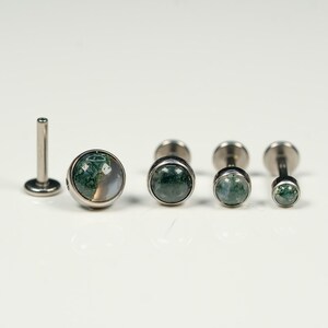 May include: Set of five silver body jewelry pieces with green and white agate stone accents. The jewelry pieces are different sizes and are arranged in a row on a white surface.