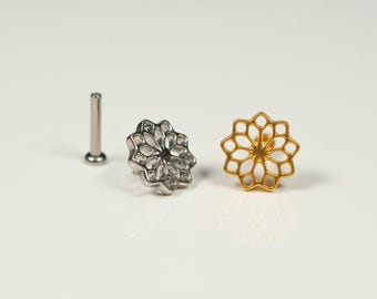 以下が含まれることがあります： 幾何学的な花のデザインが施された、銀と金の装飾的な鼻のリングが2つ。リングは白い背景に置かれています。