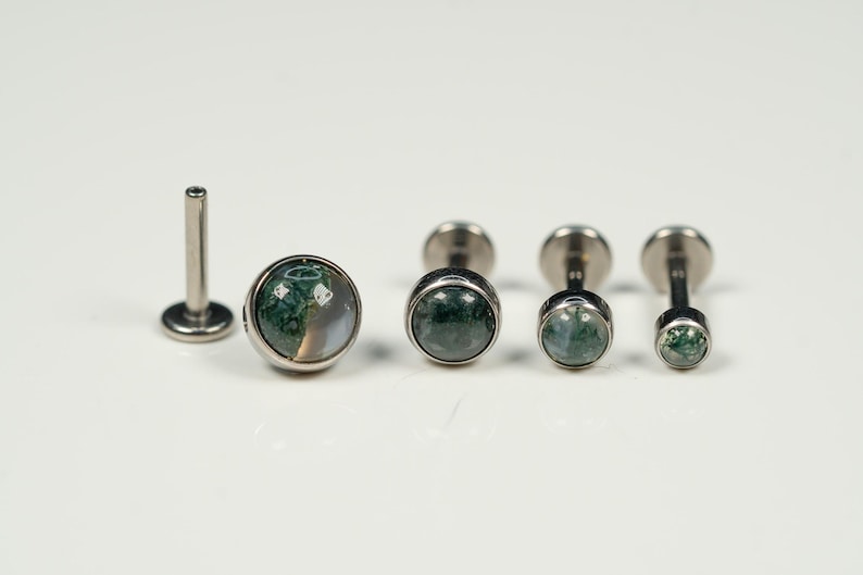 May include: A set of four silver body jewelry pieces with green and white agate stone accents. The jewelry is in various sizes and is displayed on a white surface.