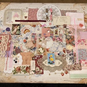 Puede incluir: Un collage de objetos efímeros vintage, incluyendo encajes, retazos de tela, botones y sellos, dispuestos sobre una superficie de madera envejecida. La paleta de colores incluye rosas suaves, cremas y estampados florales. La palabra "Morning" es visible.