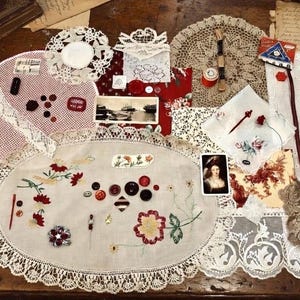 Puede incluir: Una colección de suministros de costura y artesanía vintage, que incluye tapetes de encaje, tela bordada, botones y pequeñas imágenes enmarcadas. La paleta de colores incluye tonos rojos, blancos y marrones, creando una estética nostálgica.