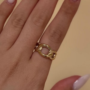 May include: Gold chain link ring with a textured finish. The ring is worn on a finger with light skin tone.