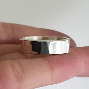May include: A silver hammered band ring with a smooth, polished finish.