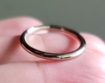 Puede incluir: Un anillo de banda de plata simple, usado en un dedo.