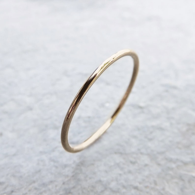 Pu&ograve; includere: Un semplice anello a fascia d'oro. L'anello &egrave; sottile e ha una finitura liscia e lucida.